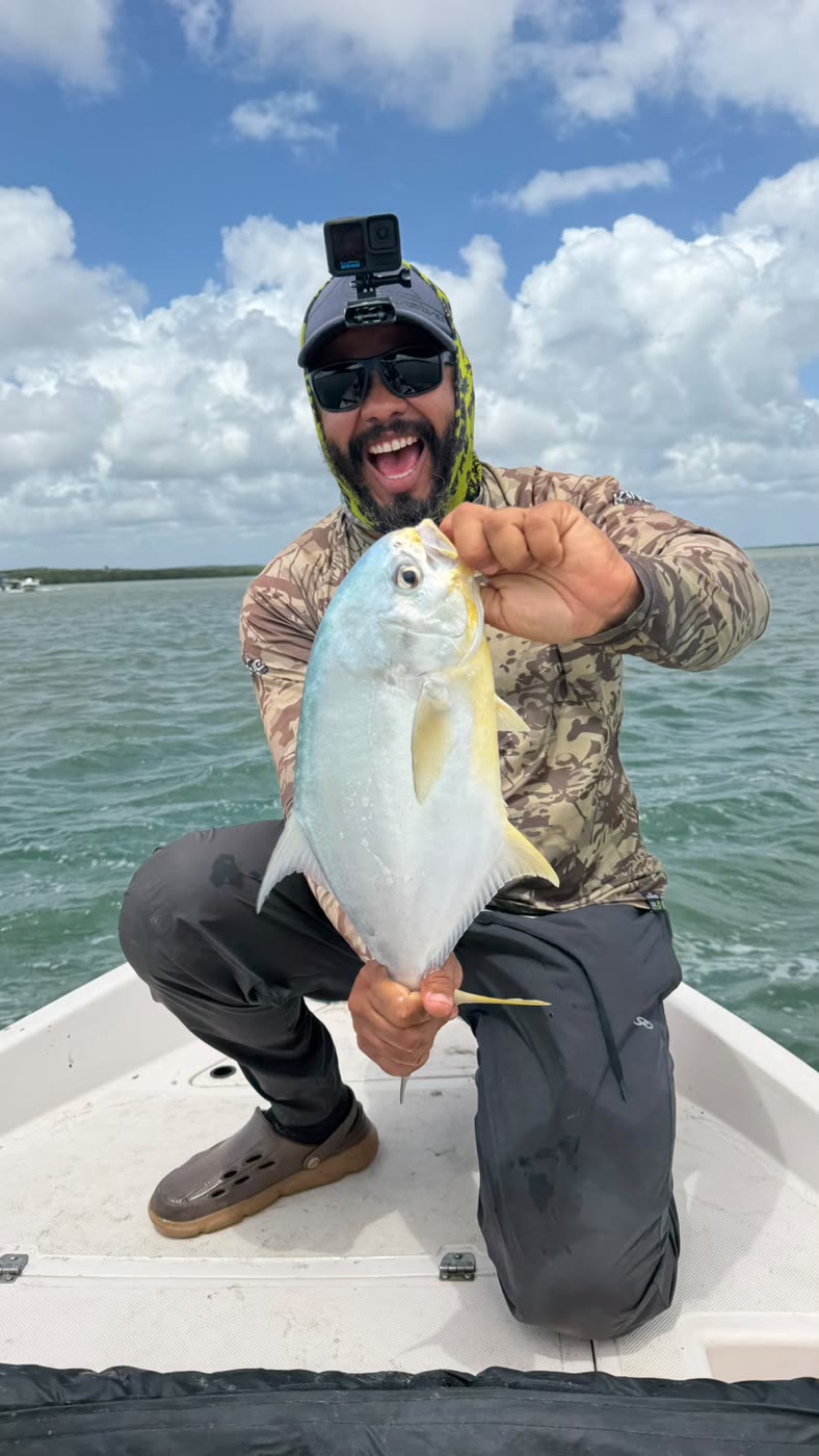 Pescador comemorando com um pampo na proa do barco